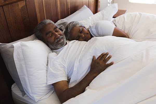Senior couple sleeping together in bedroom